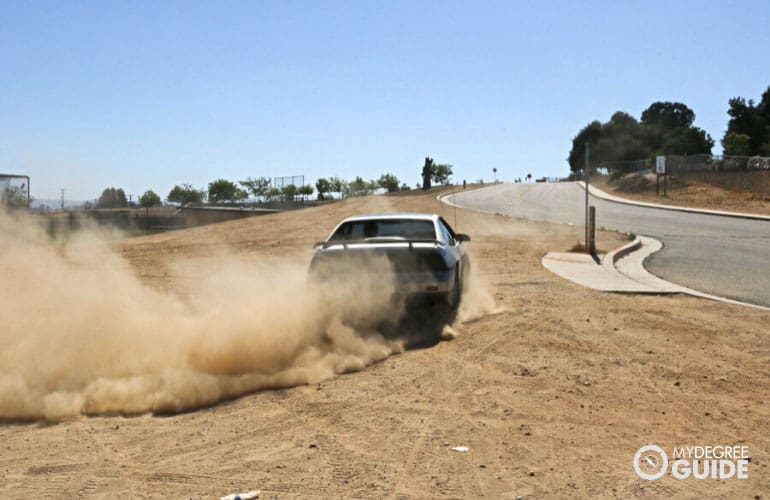 sports car peeling out leaving dust behind