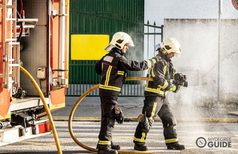 firefighters pulling a water hose to put out a fire