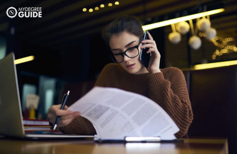 accountant working on documents while talking to a phone