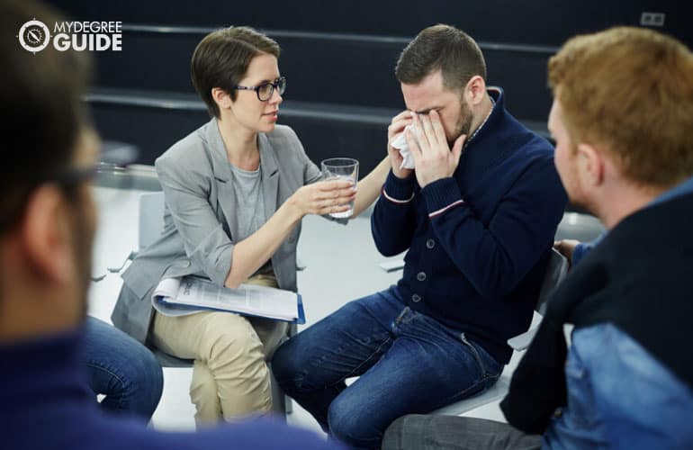 addiction counselor giving her patient a glass of water during therapy session