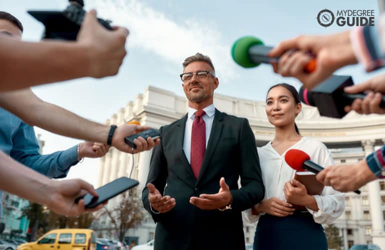 politician and his assistant being interviewed by media