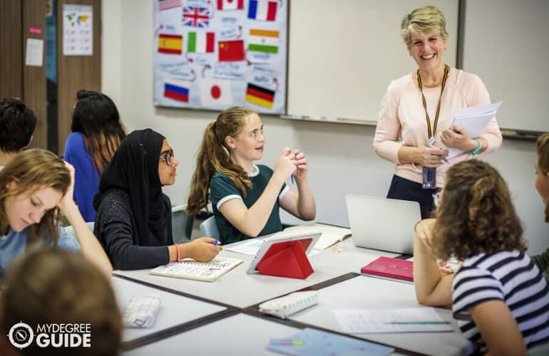 high school teacher talking to a group of diverse students