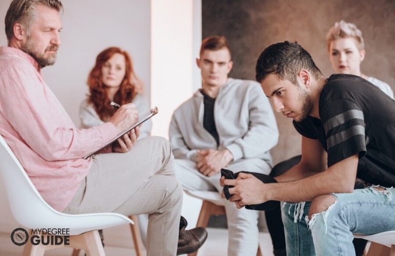 Addiction Counselor listening to his patients during group counseling