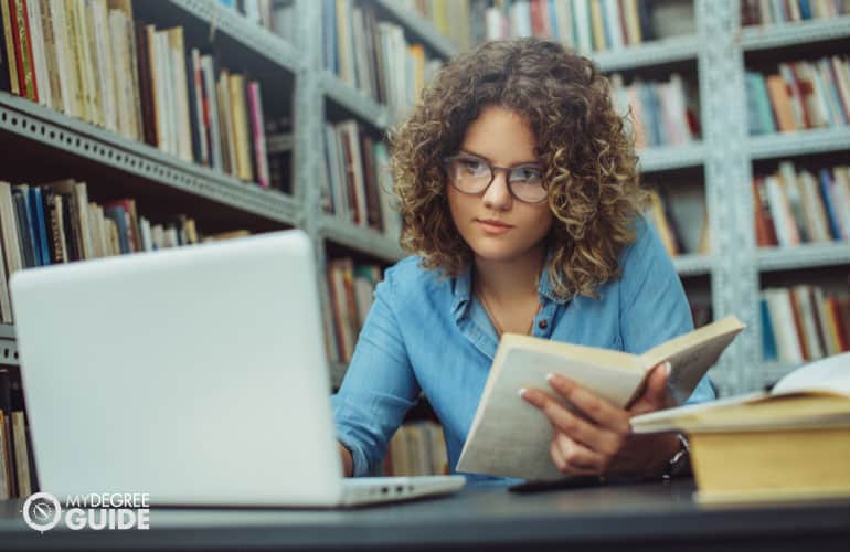 doctorate student studying on her computer in a college library