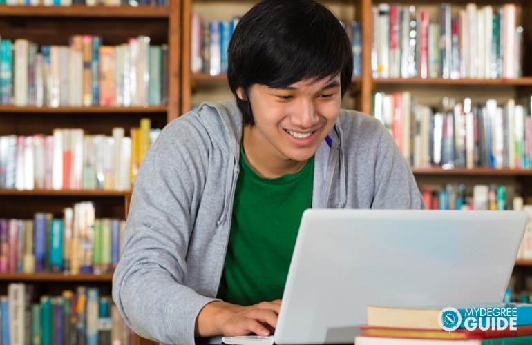 Bachelors in Mechanical Engineering student studying on his laptop in a library