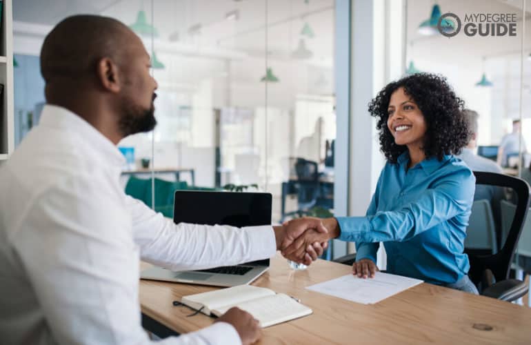 human resource person shakes hand with interviewer during interview