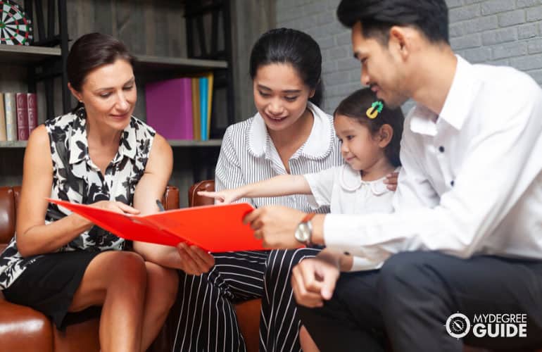 psychologist giving a document for signing to an Asian family for adoption