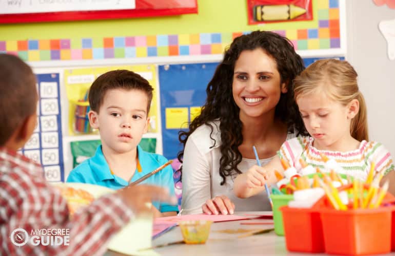 early childhood education teacher assisting her students