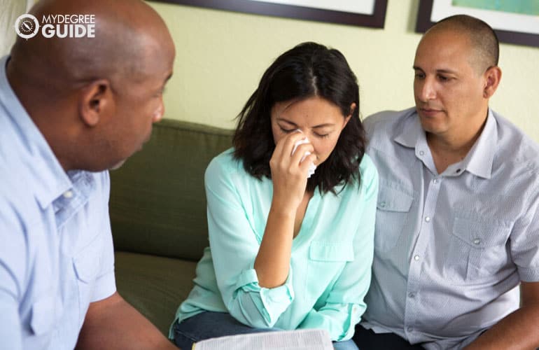 counselor holding a bible while talking to a couple