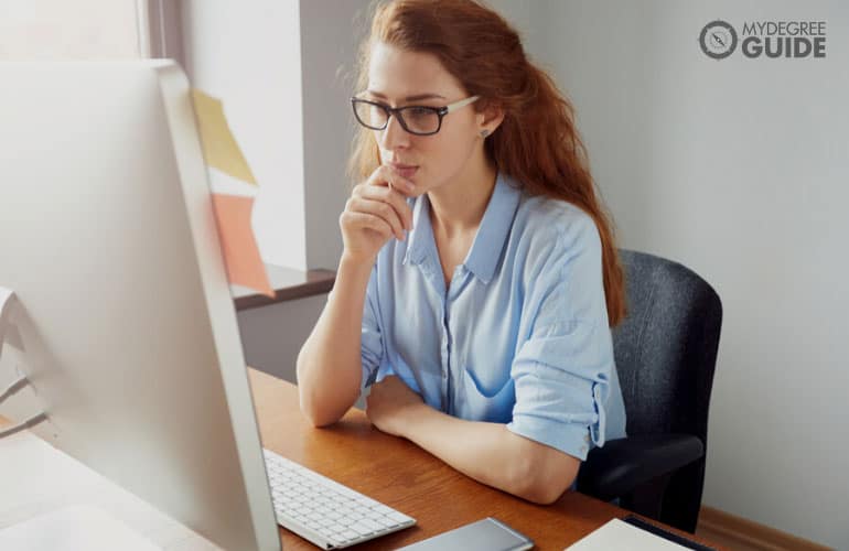 female pondering as she look at her computer