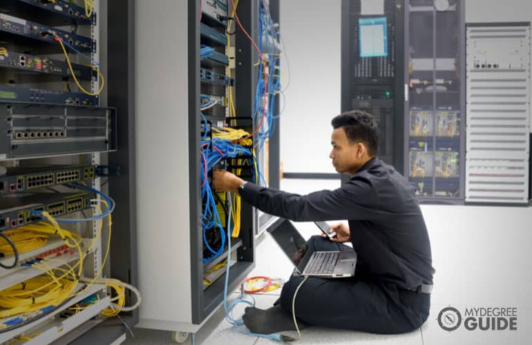 network administrator fixing the cables in IT control room