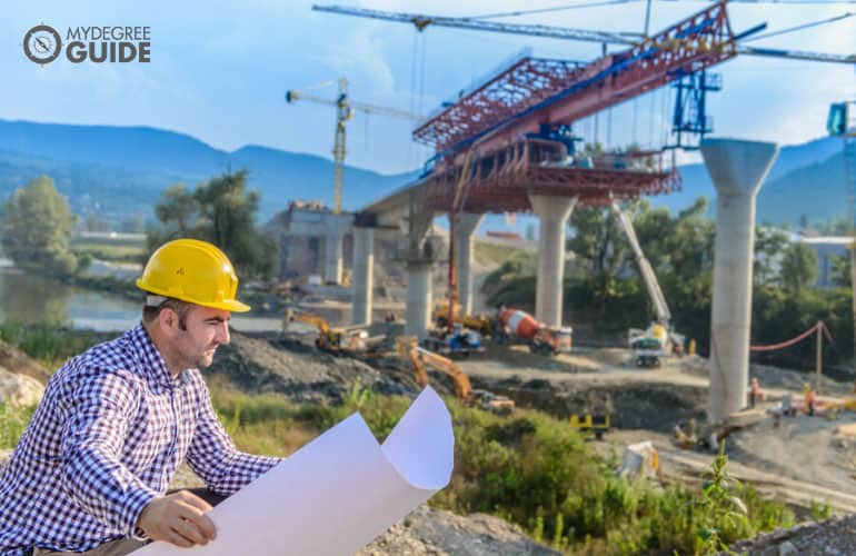 construction worker looking at construction plan for highway bridge