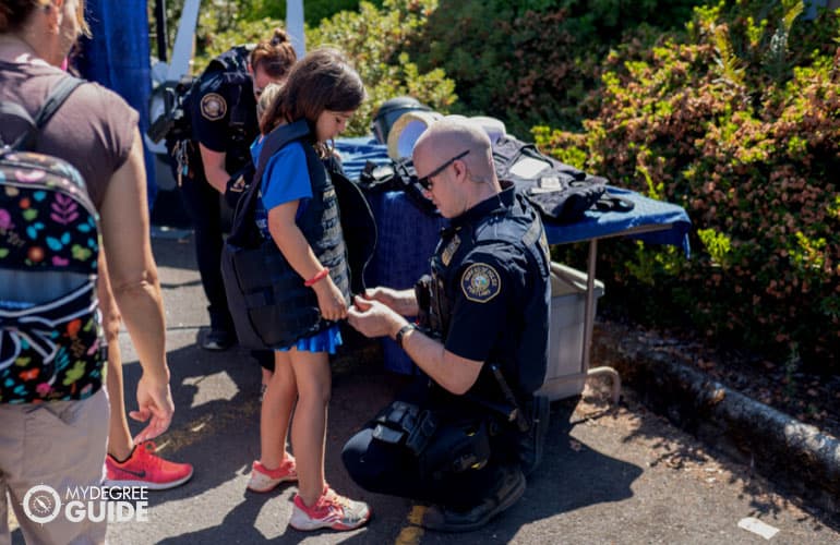 policeman helping a child wear a Kevlar vest at an event