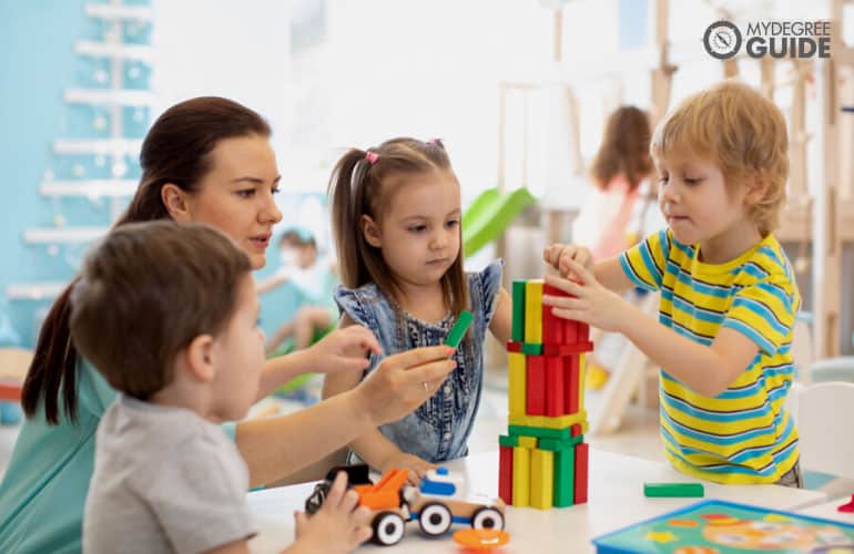 early childhood education teacher helping her students during playtime 