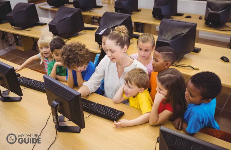 teacher showing the kids how to use computer