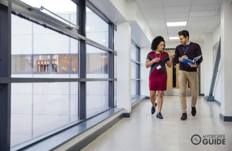 two educators walking in a university hallway