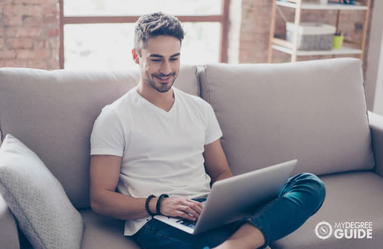 Sociology Degree student studying on his computer in a sofa