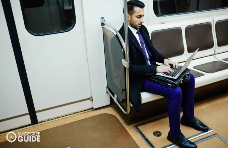 a commuter in professional wear working on his laptop