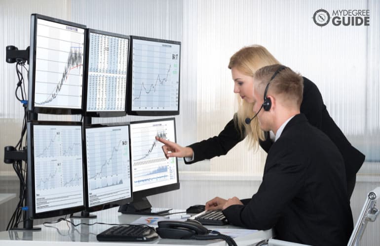 people analyzing data displayed on computer screens