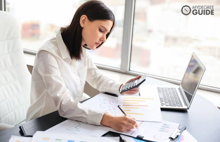 forensic accountant checking documents and working on her laptop