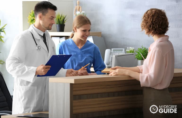 health services administrator assisting a patient in the reception area