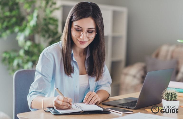 education executive sitting at desk writing notes