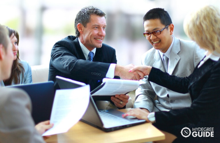 diverse group of managers shaking hands in a meeting