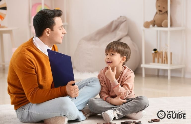 Speech pathologist guiding a child read basic words