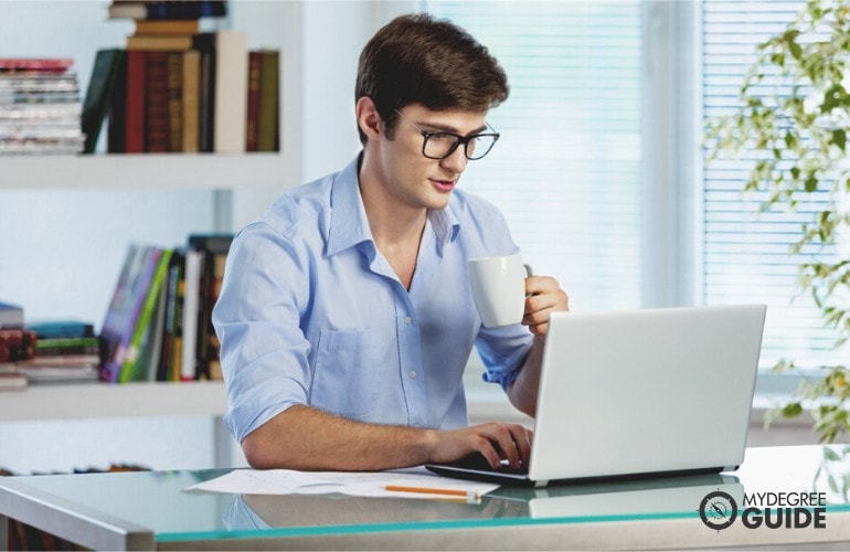 Master’s in Healthcare Management Degree student studying on his laptop