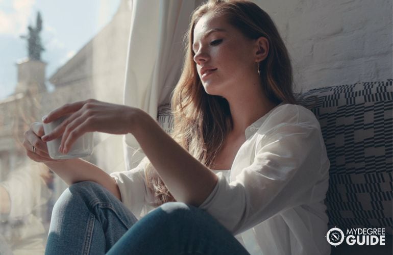 college student sitting by dorm window