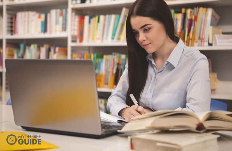 female studying with books and a laptop