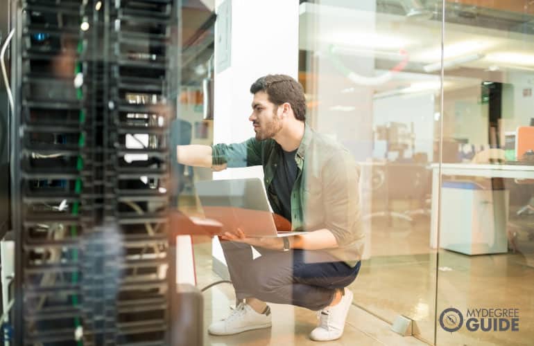 network administrator fixing cables in data room