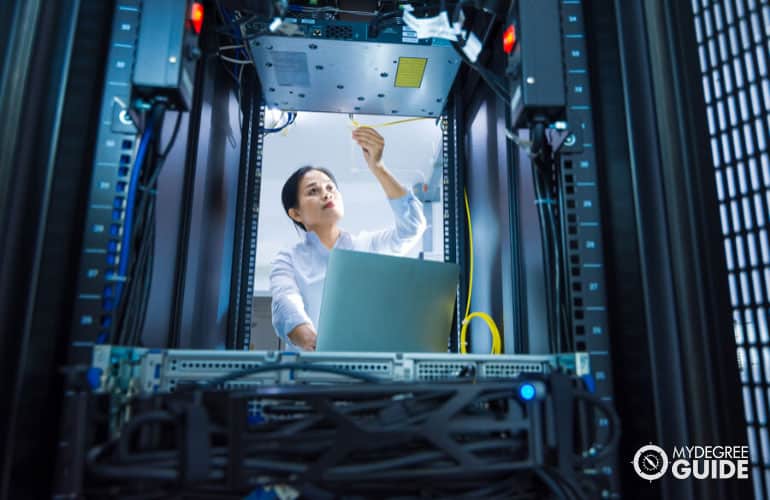 information systems manager fixing cables in data room