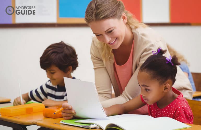 Early Childhood Education teacher teaching young students how to write