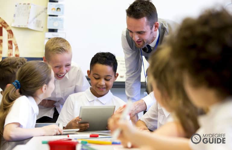 elementary teacher teaching his students using a digital tablet