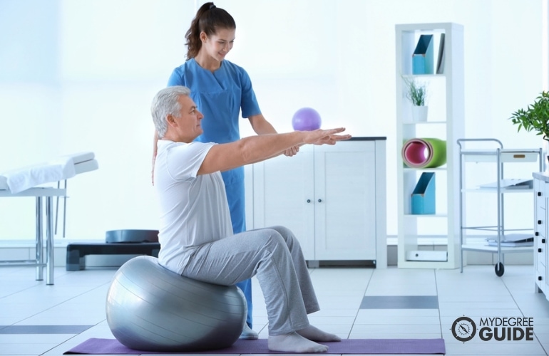 Physical Trainer assisting a man while exercising