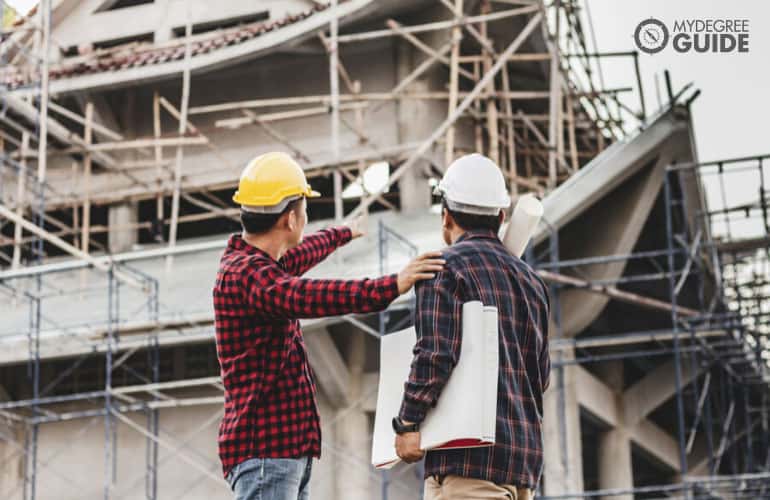 male construction engineers looking at on-going construction at residential buildings