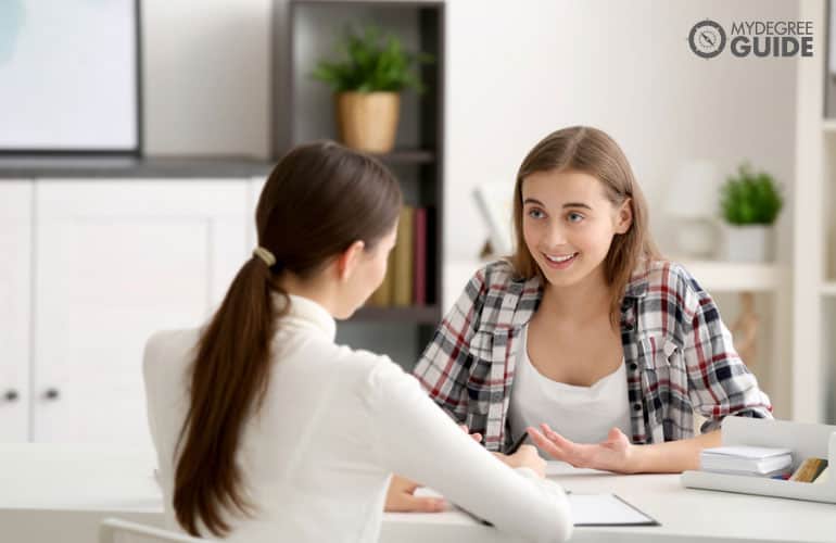 psychologist talking to a teenage girl in her office