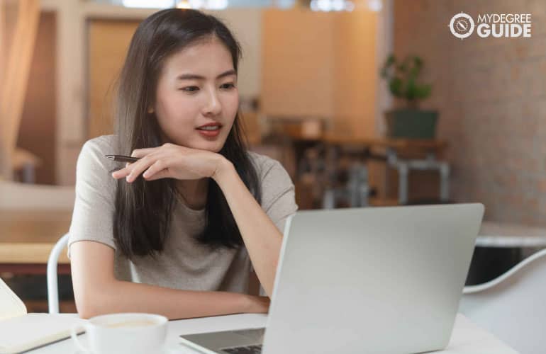 social work online graduate reading on laptop