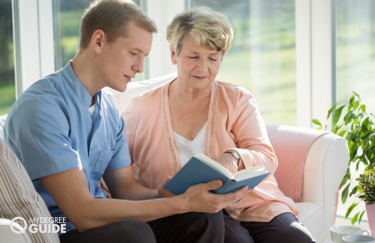 social worker helping an elderly woman in reading her book