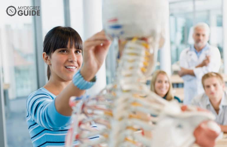 medical students studying a model skeleton