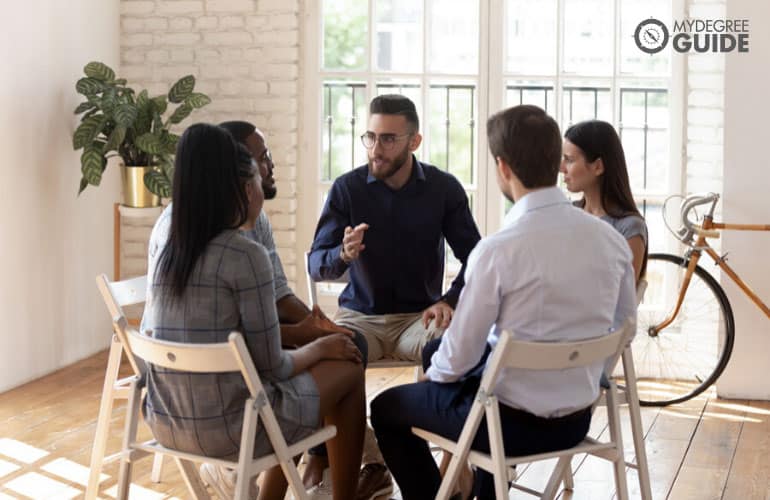 psychologist talking to a group of people during therapy session