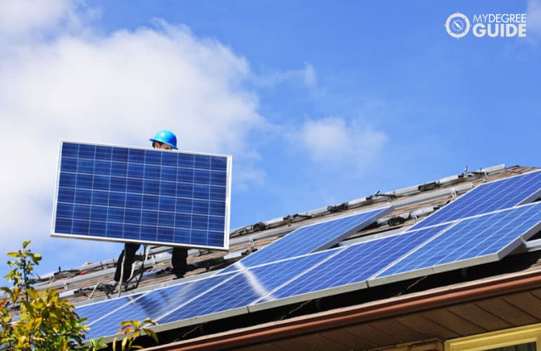 construction worker installing solar panels on a roof