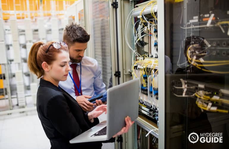 systems engineer using laptop to analyze server in server room