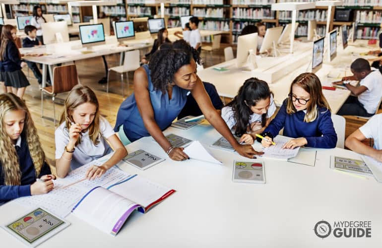 teacher teaching elementary pupils in a library