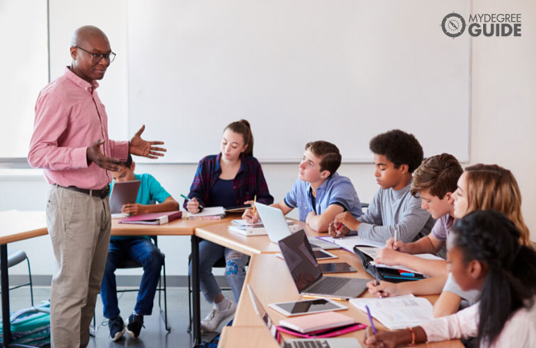 teacher teaching high school students in a classroom