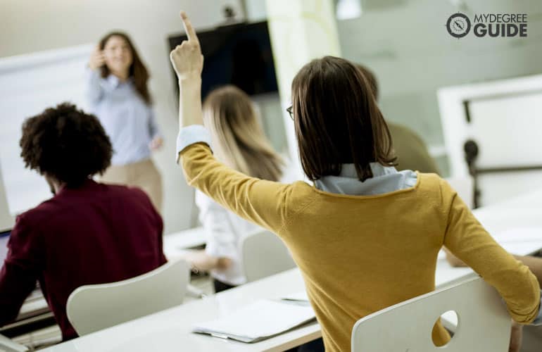 university student raising her hand to ask questions