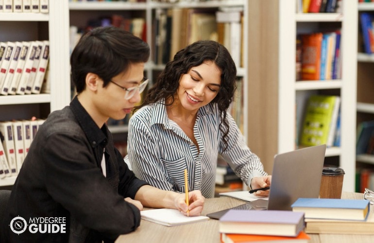 academic advisor helping her advisee in library