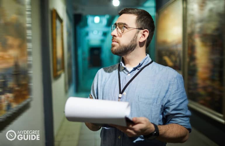 museum curator checking the painting exhibits in a museum